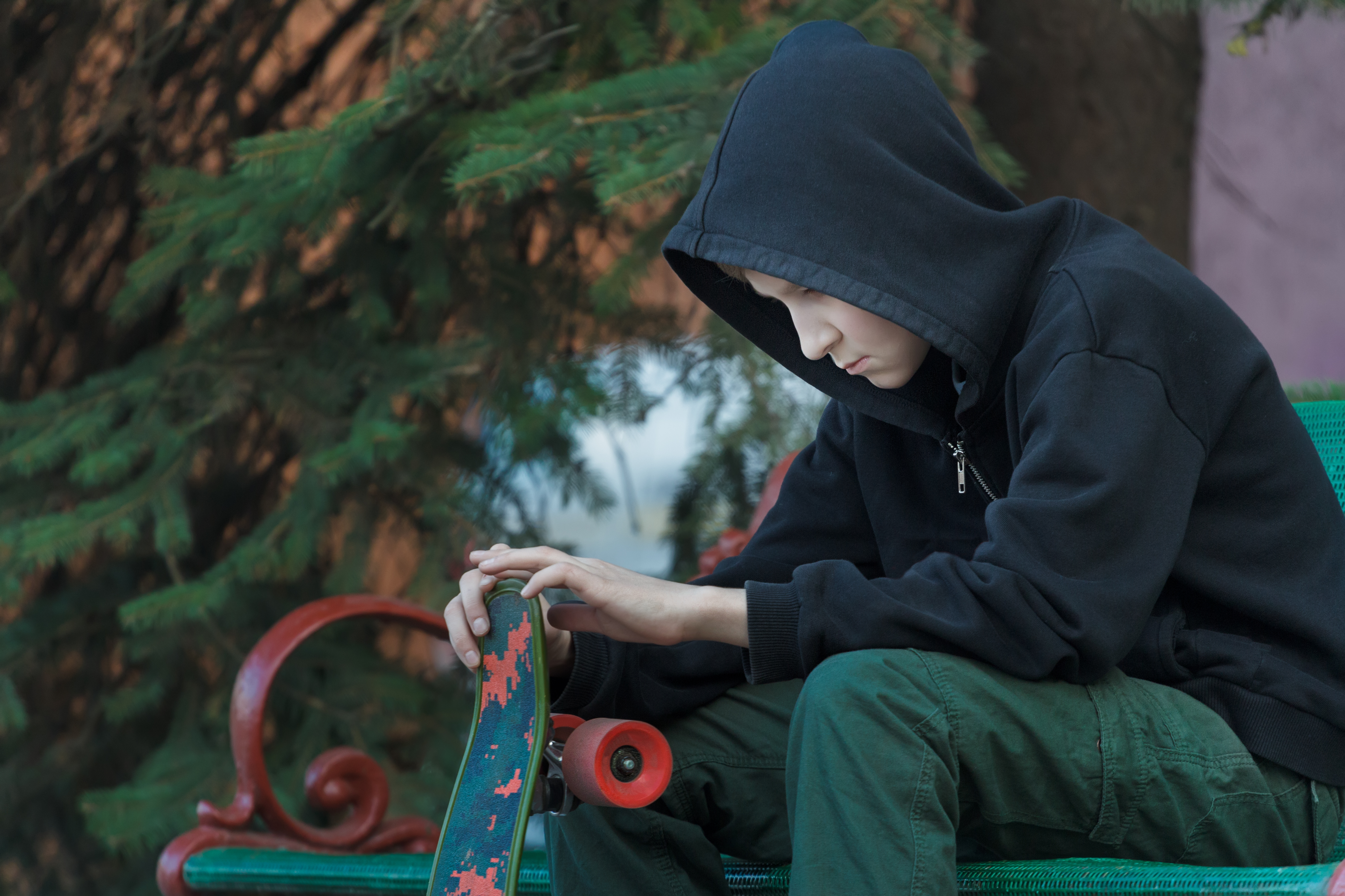 Child sitting with skateboard looking sad