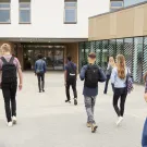 Photo of many young people walking into a building