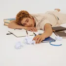 Image of stressed student laying on books