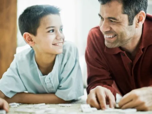 A man plays dominoes with a boy