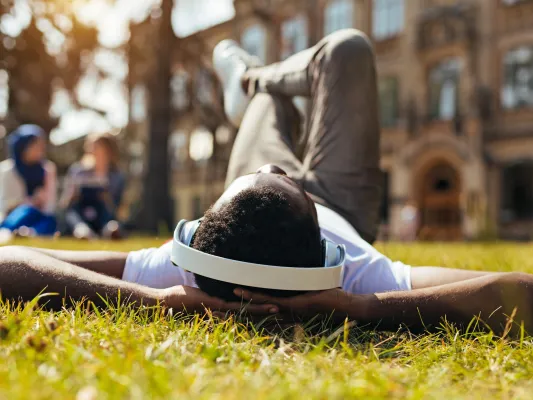 Young man laying in grass with headphones on 