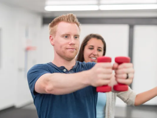 Photo of a young woman volunteering in a VA clinic with a veteran in physical therapy