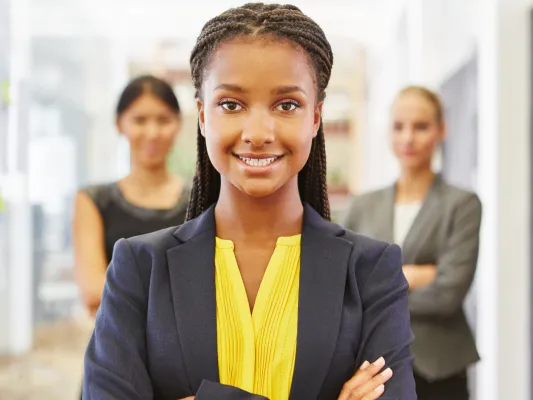 Young woman looking at the camera. Two other people stand behind her.