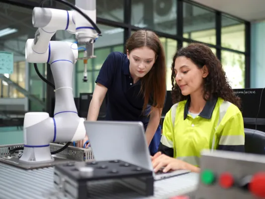 Young woman working at a computer with an adult mentor