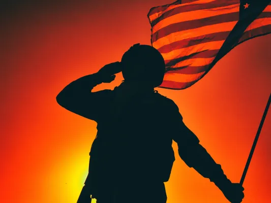 Silhouette of a soldier saluting and holding a flag
