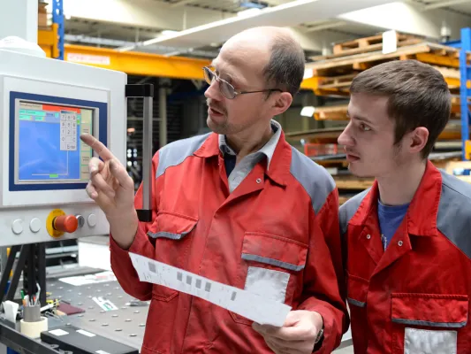 Teen and adult looking at a computer on a job site