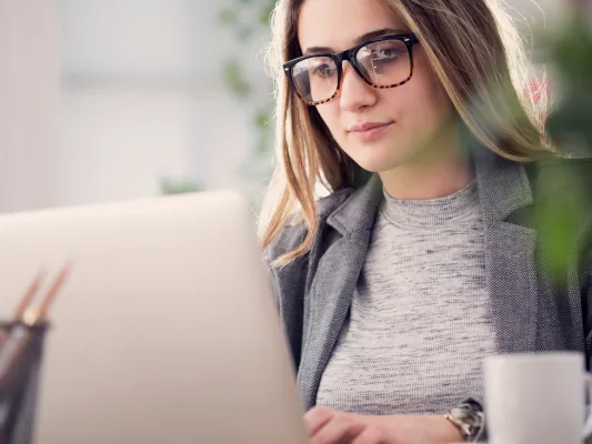 Young woman with glasses working at a laptop