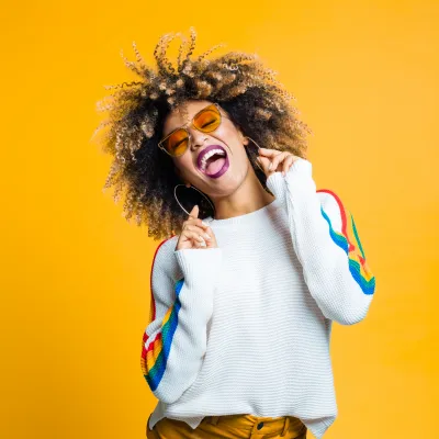 Young Black woman with an excited expression in front of a yellow background.