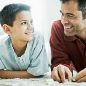 A man plays dominoes with a boy