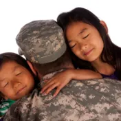 A man in uniform hugs two children