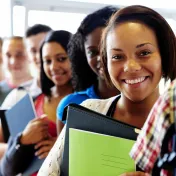 Line of students at school smiling with backpacks and school supplies