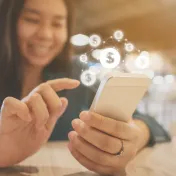 Young woman using phone with graphic of dollar signs above phone