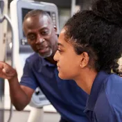 Photo of a mentor teaching a young woman about a machine during job training