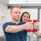 Photo of a young woman volunteering in a VA clinic with a veteran in physical therapy