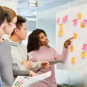 Group of young workers looking at a white board with sticky notes