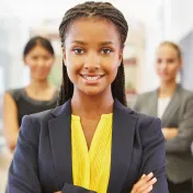 Young woman looking at the camera. Two other people stand behind her.