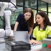 Young woman working at a computer with an adult mentor